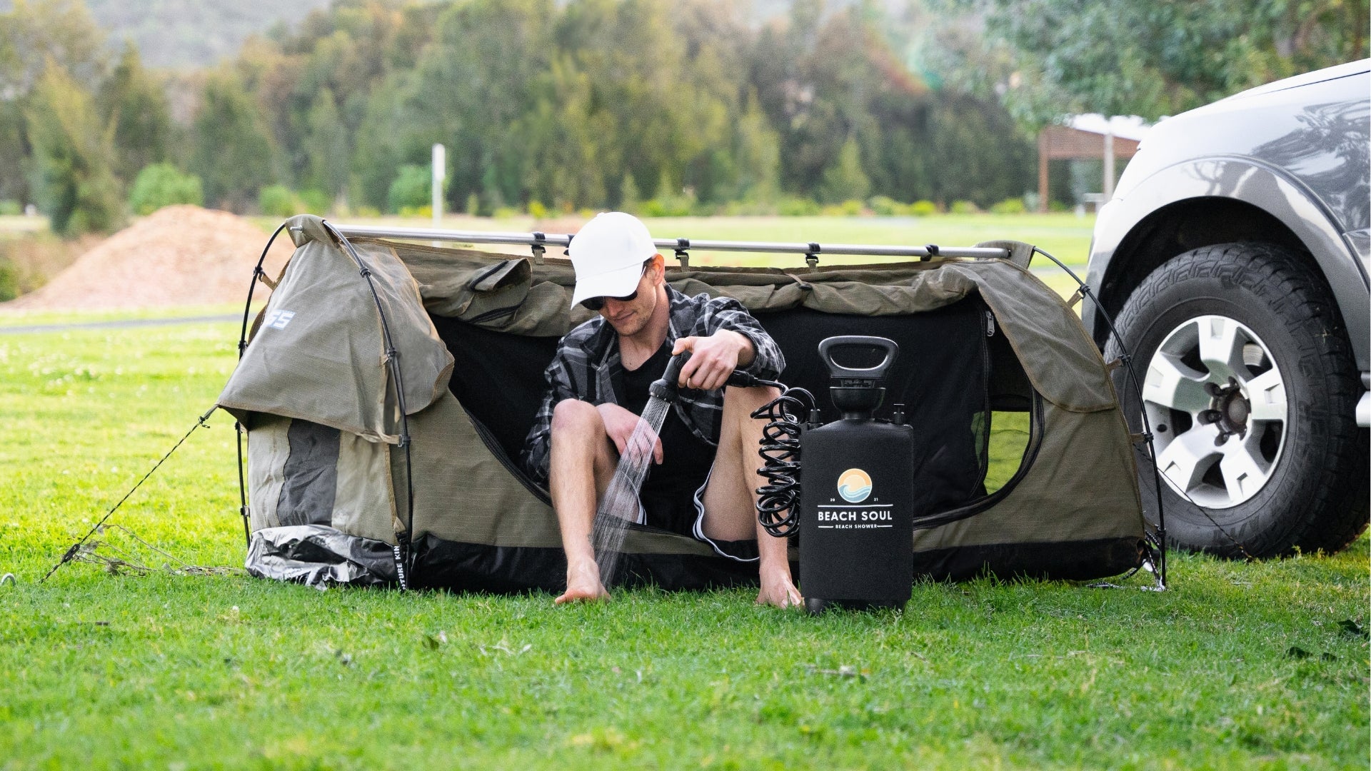 Beach Soul portable shower set up beside a vehicle and camping shower tent