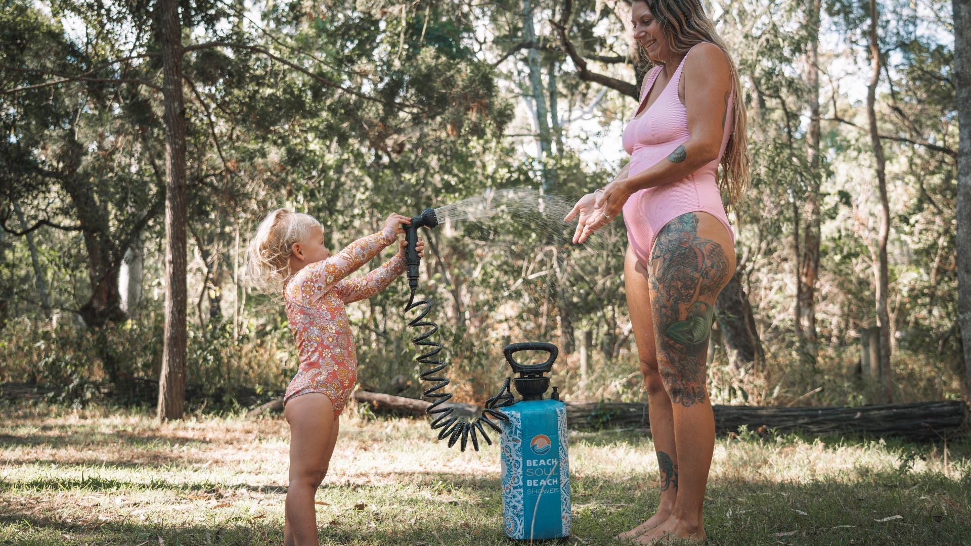 Mother supervising a child using a Beach Soul portable shower outdoors