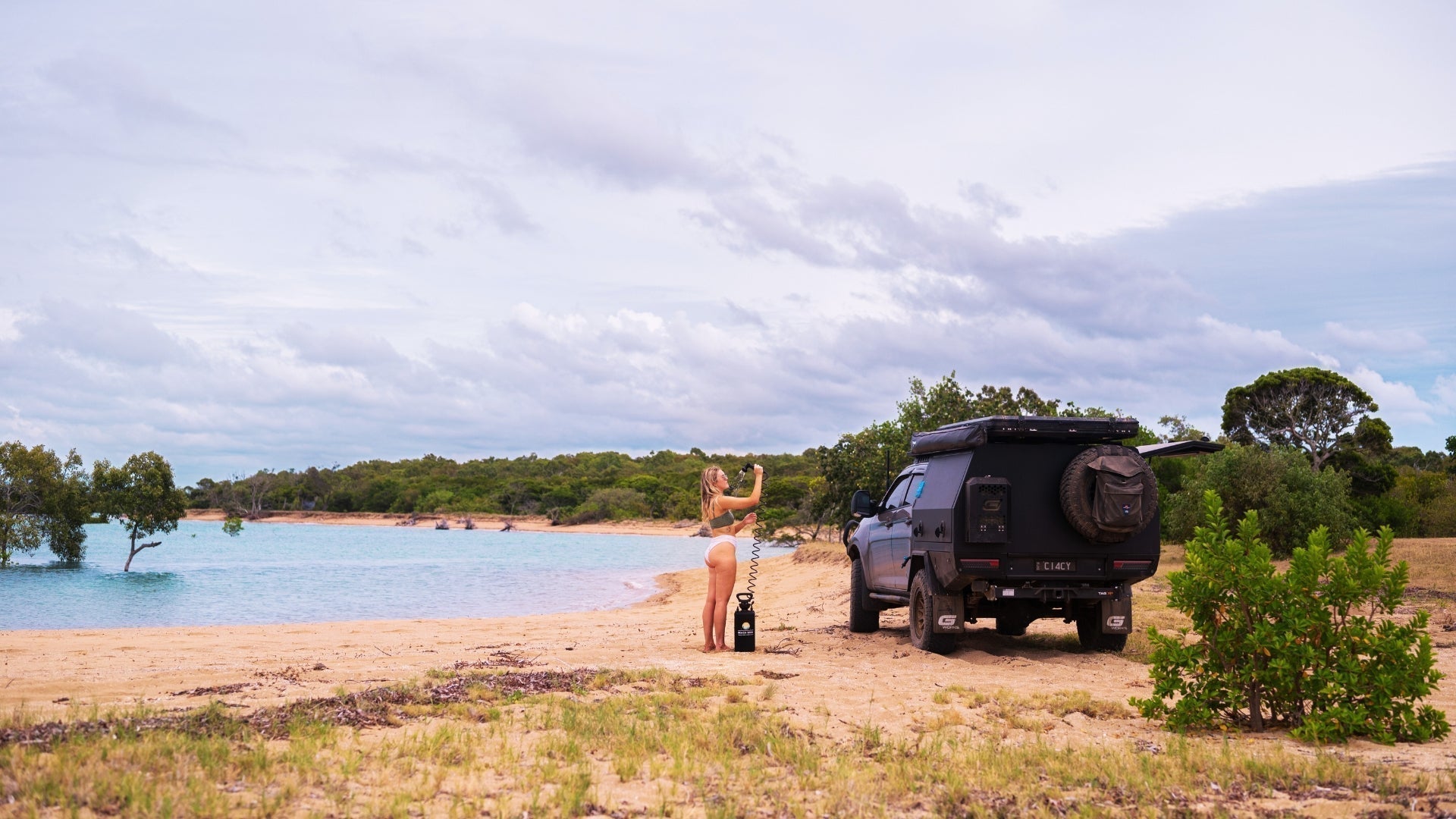 Beach Soul portable shower being used beside a four-wheel drive at an off-grid beach campsite