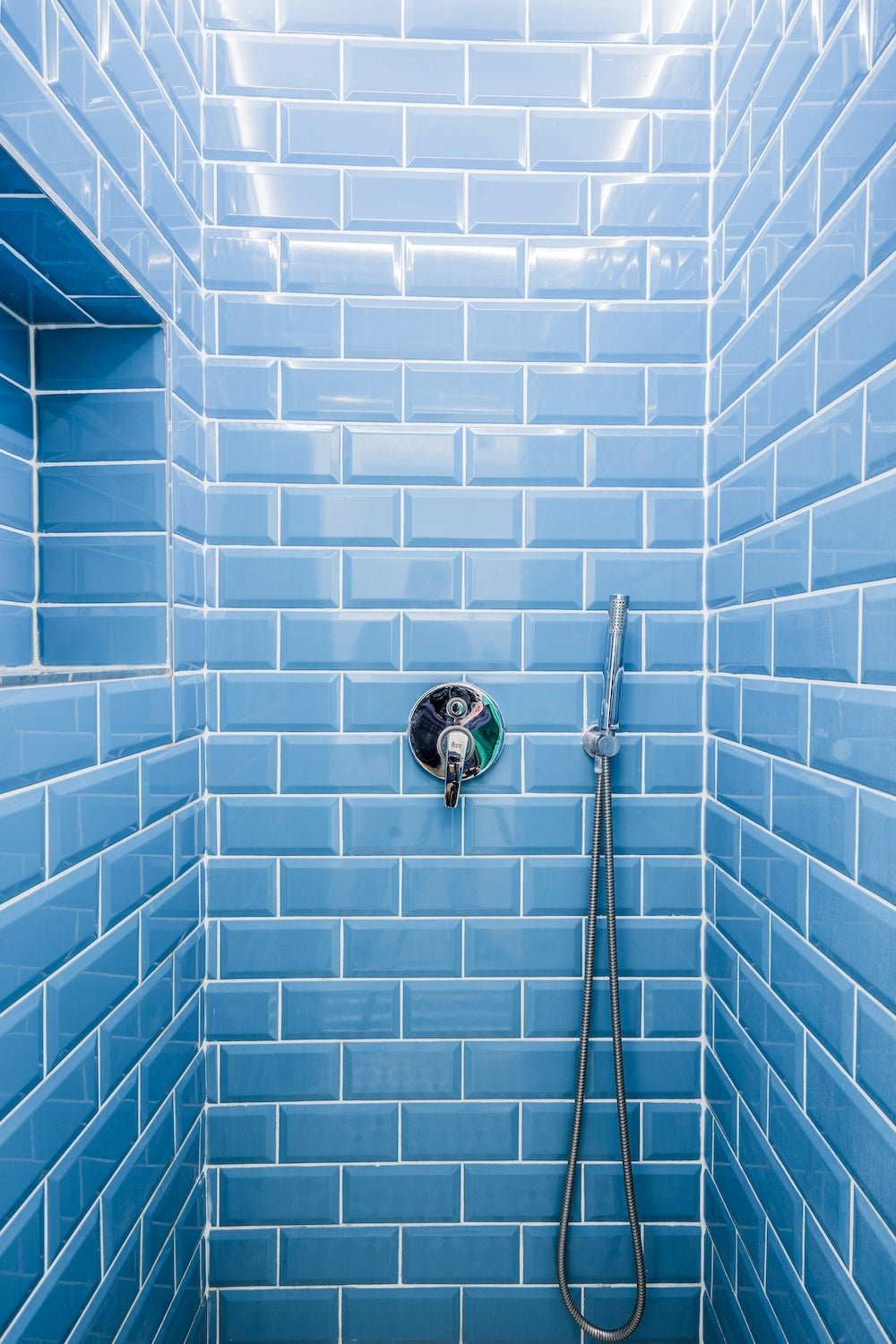Bathroom shower head against blue tiled wall