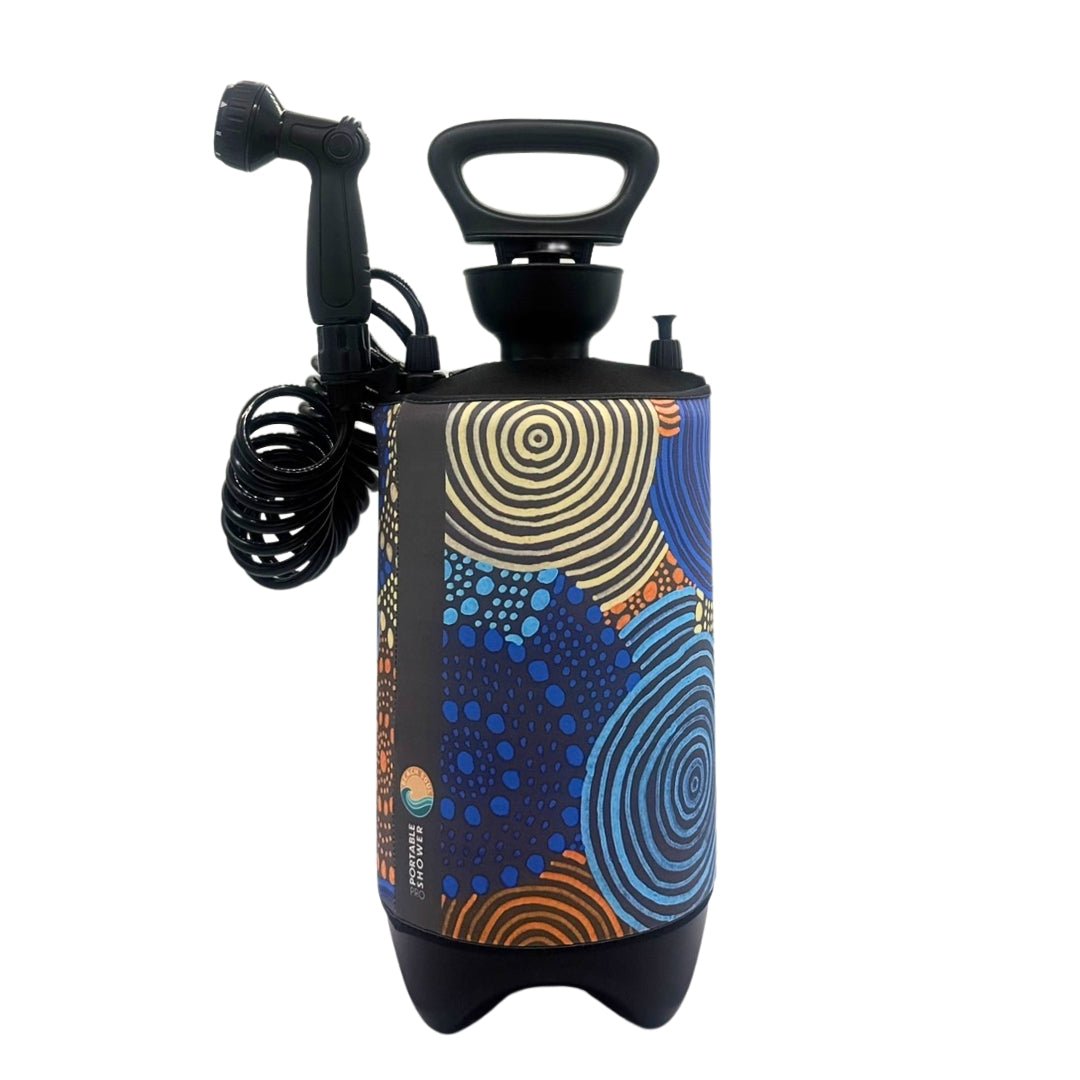 A portable shower unit featuring vibrant Aboriginal-inspired art with concentric circles and dot patterns in blue, orange, and yellow, complete with a black coiled hose and shower head