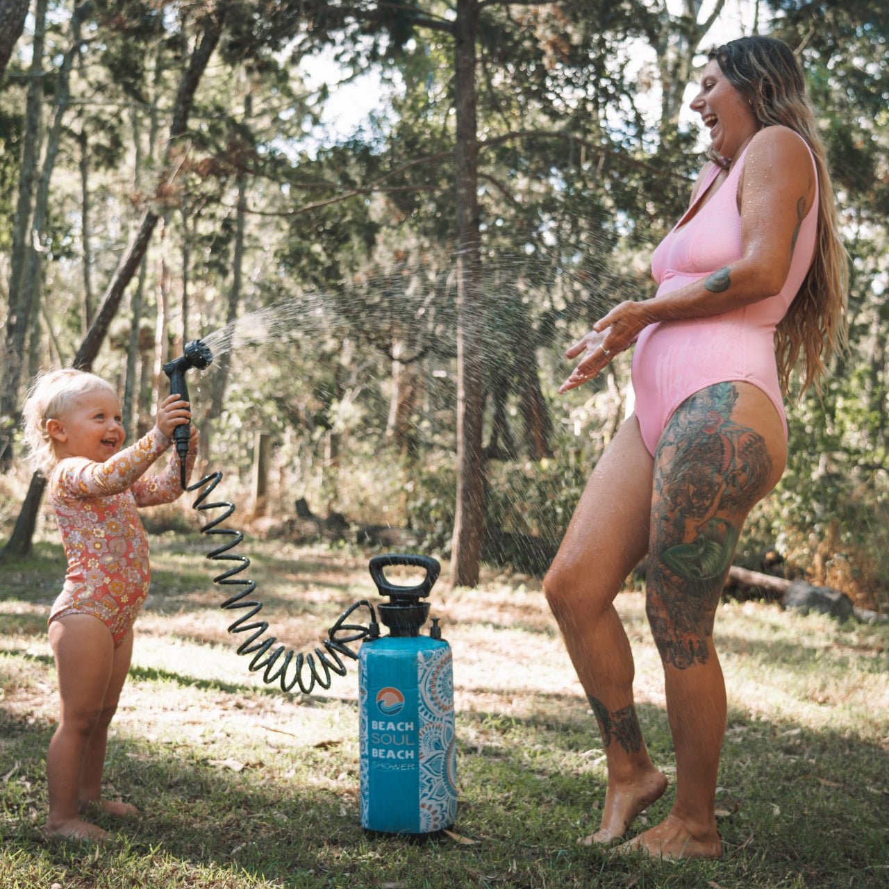 Woman using the Bliss Out portable shower to rinse a child outdoors