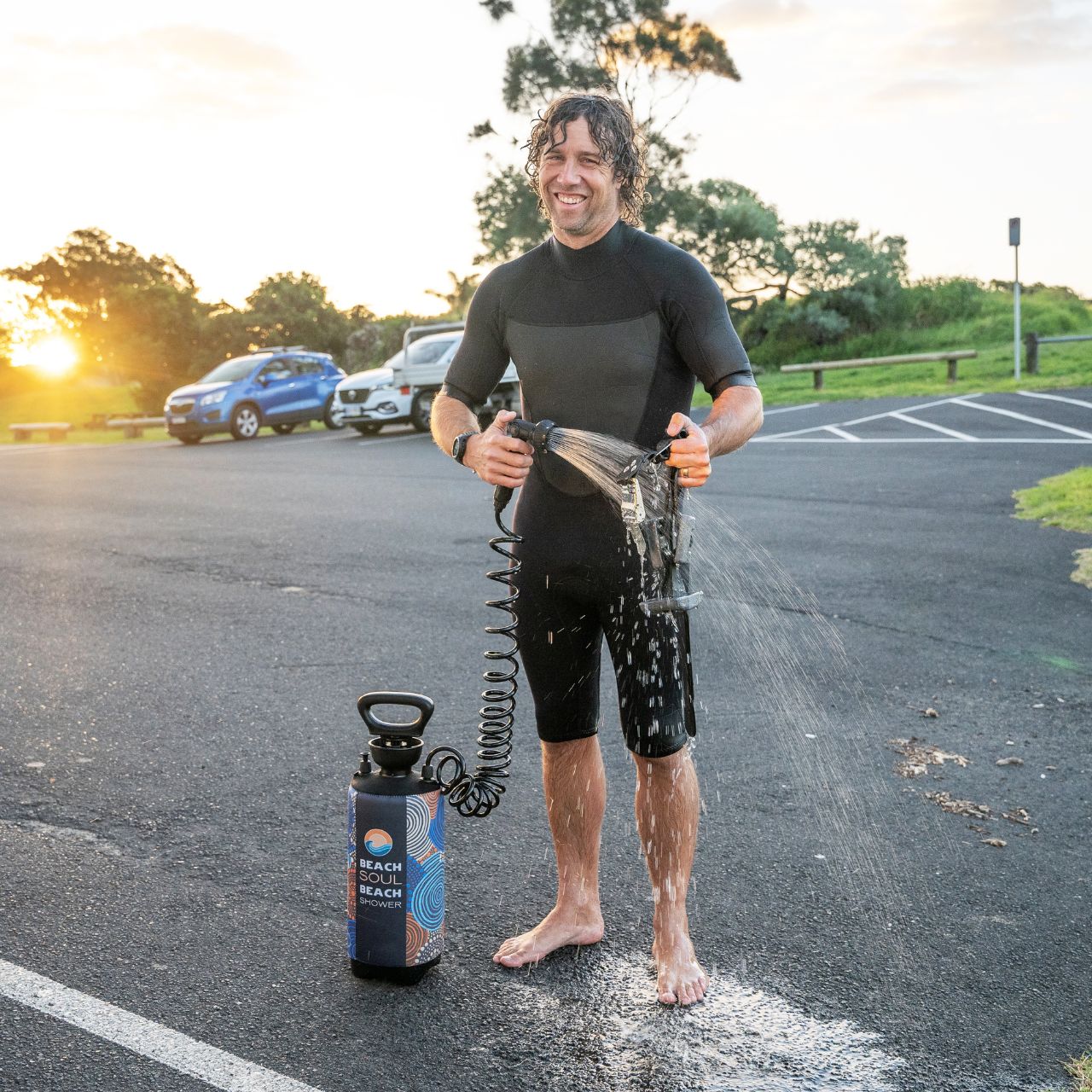 Man using the Jamigam portable shower to rinse off outdoors