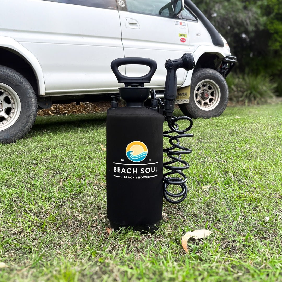 Beach Soul portable shower beside a four-wheel drive with the shower head held by the Tank Clip