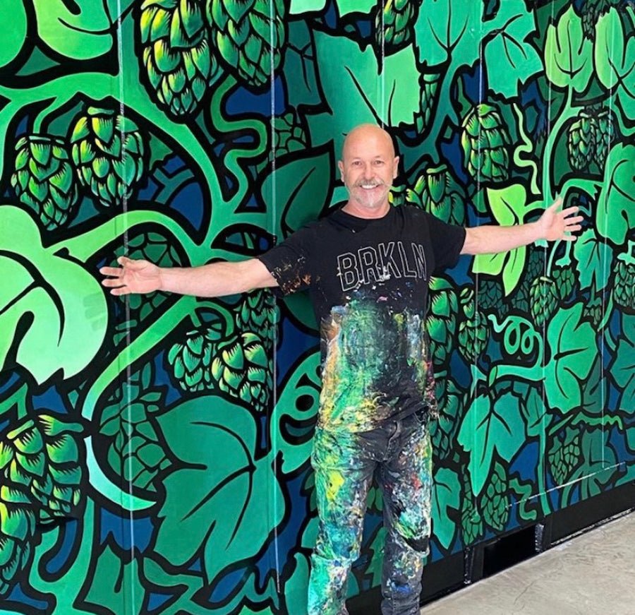Artist Steven Bordonaro standing in front of his green botanical mural