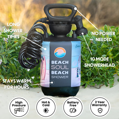 A Beach Soul Beach Shower, a black portable shower bottle with a coiled hose and a colorful graphic sleeve depicting a sun, wave, pink surfboards, and a beach van, placed on sand amid green foliage, emphasized by text stating no power needed, a 10 mode showerhead, and long warm shower times