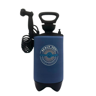 A dark blue Beach Soul Portable Shower Pro with a black handle, coiled hose, and shower head, featuring a circular white sun and wave logo on its insulated body