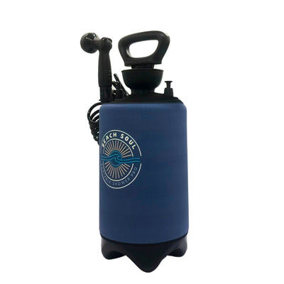 A dark blue Beach Soul Portable Shower Pro portable shower system with a white sun and wave logo, featuring a black pump handle and showerhead on a white background