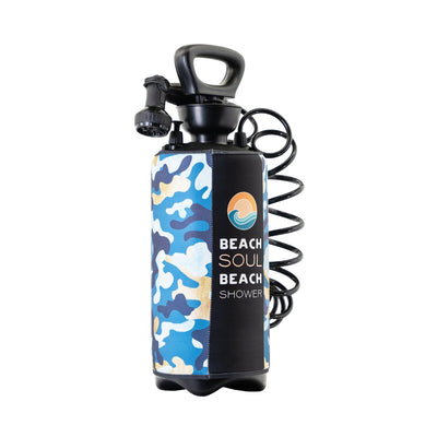Product photograph of a Beach Soul portable beach shower on a white background, featuring a blue and tan camouflage neoprene sleeve, a black handle, and a brand logo with an orange sun and blue wave design