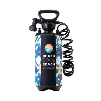 Product photo of a Beach Soul portable beach shower featuring a blue, beige, and white camouflage pattern sleeve with "BEACH SOUL BEACH SHOWER" text and an orange sun and blue wave logo, connected to a black coiled hose and adjustable spray nozzle, all isolated on a white background