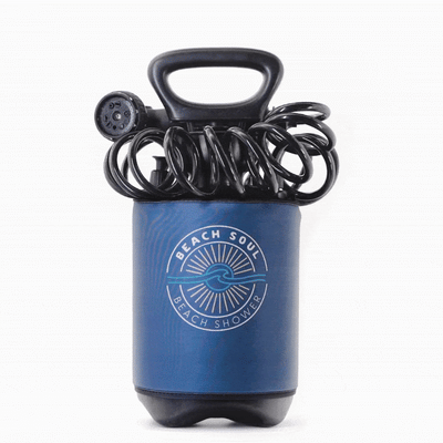 A Beach Soul portable shower system featuring a dark blue insulated tank, a black coiled hose, multi-setting showerhead, and a prominent circular white logo with a sun and wave design