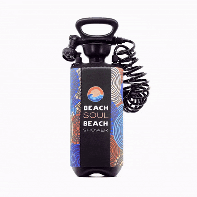 Product photography of a Beach Soul Beach Shower, a black portable unit featuring a vibrant blue and orange abstract patterned sleeve, a wave logo, and a coiled black hose with shower nozzle