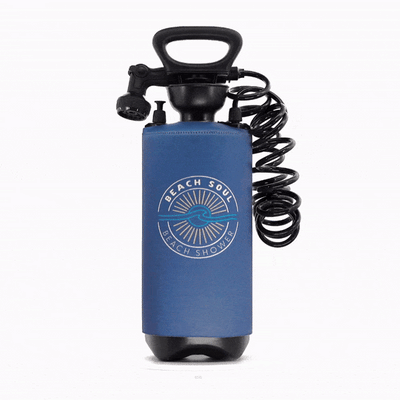 A blue portable pressure shower with a black pump handle, coiled hose, and a round "Beach Soul Beach Shower" logo featuring a sun and wave graphic