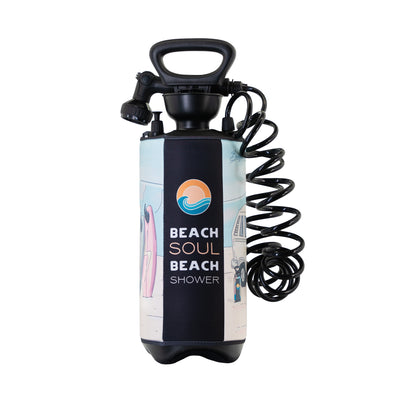 Product photography of a Beach Soul portable pressure shower featuring a black top handle, coiled hose, and a vibrant neoprene sleeve adorned with a pink surfboard, a beach camper van, and an orange sun and blue waves logo